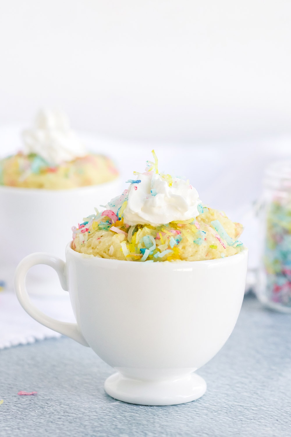 Vanilla funfetti cake with whipped cream in a mug.