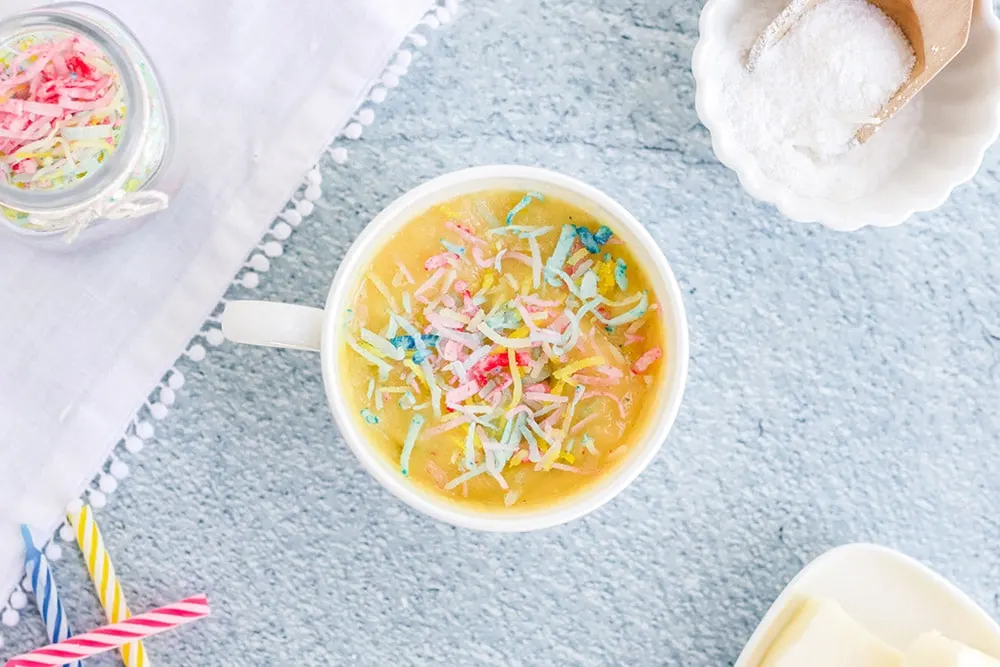 Cake batter and colored coconut shreds in mug.