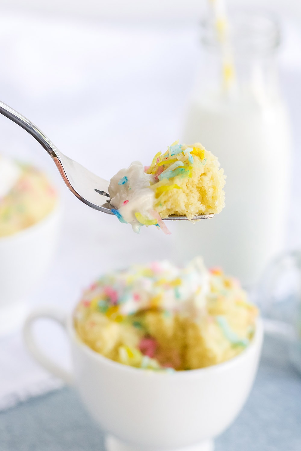 Fork full of confetti cake with mug in background.