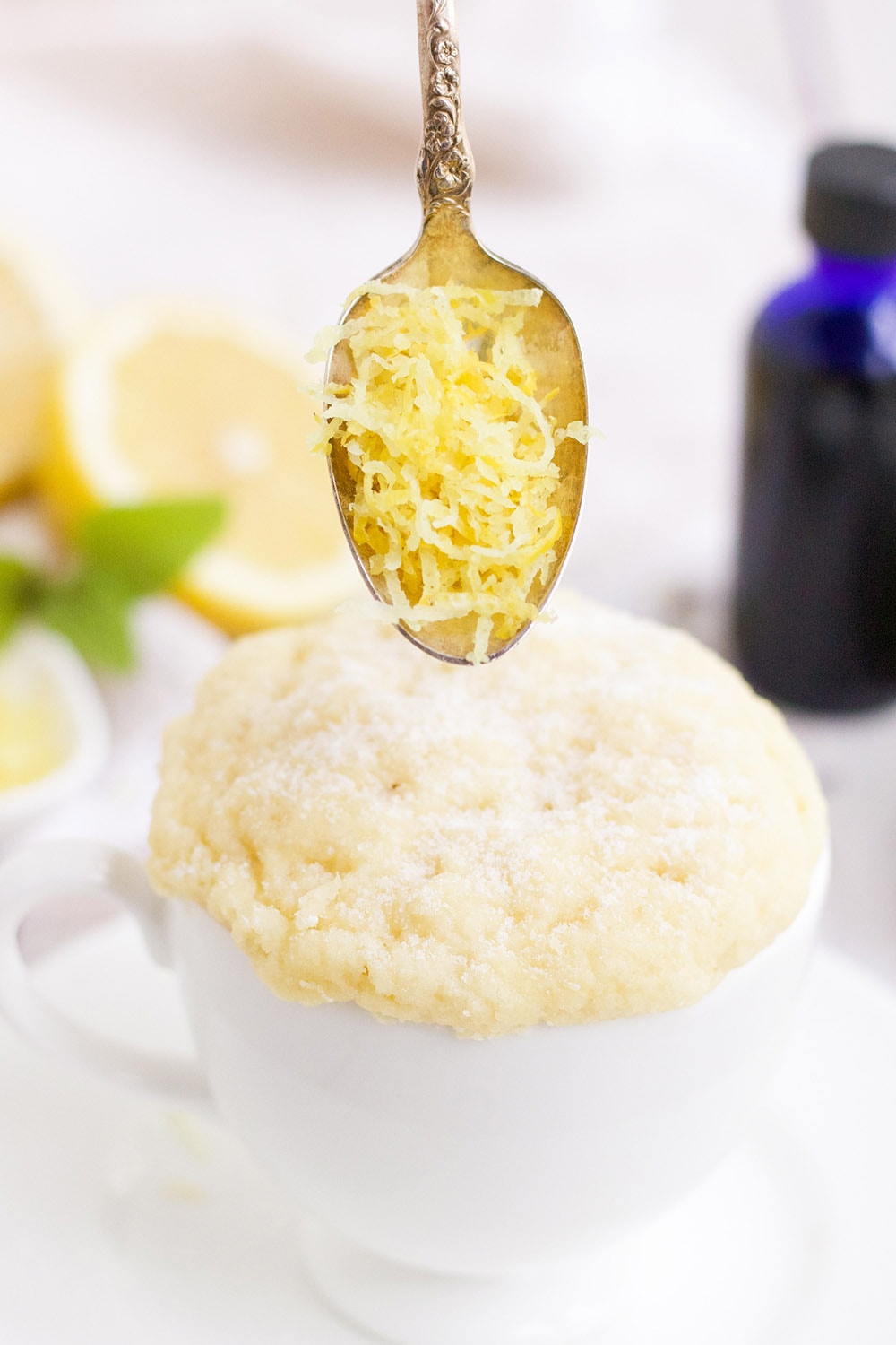 Lemon zest in a spoon over the lemon mug cake.