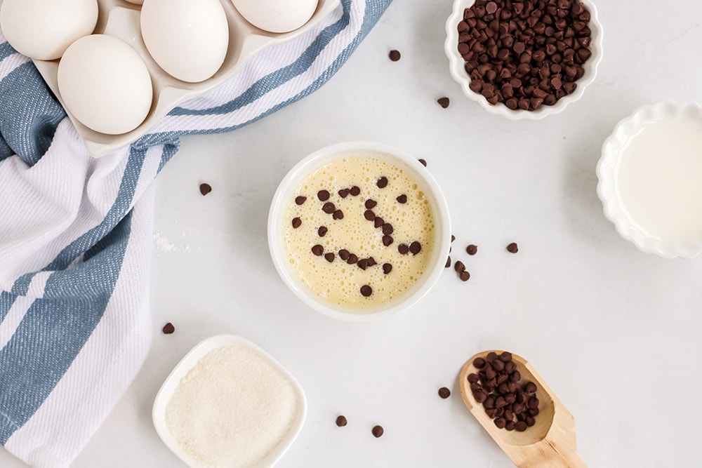 mug cake batter in a ramekin with chocolate chips and other ingredients on a table