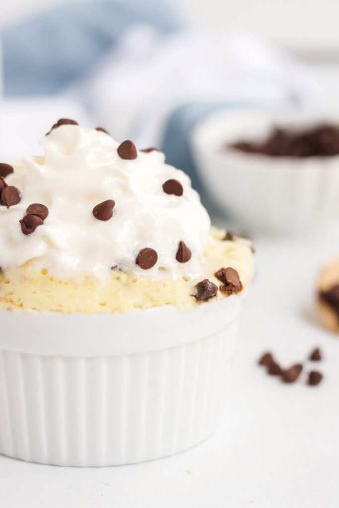 ramekin of chocolate chip cake topped with whipped cream and chips