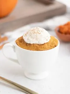 pumpkin cake in a mug by a fork and a tray