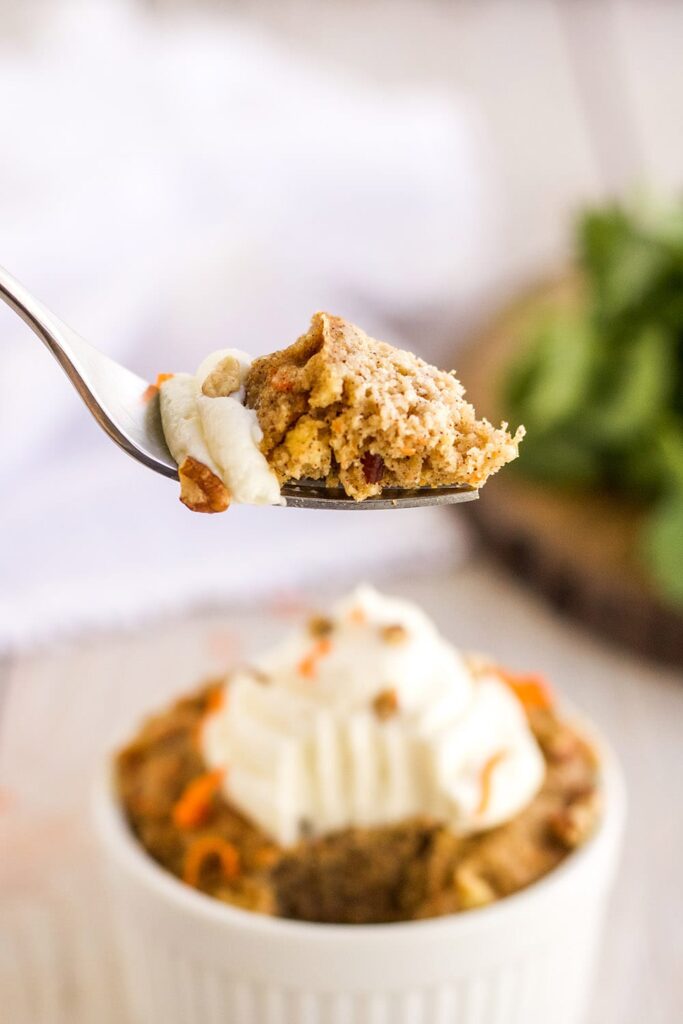 Fork full of carrot cake with the ramekin in the background