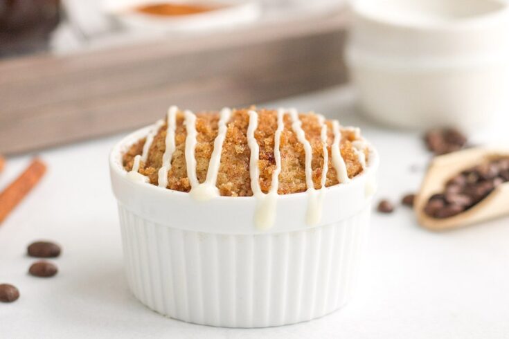 Coffee cake in a ramekin on a white table with coffee beans
