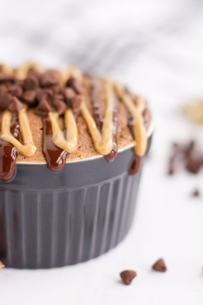 Peanut butter chocolate mug cake in a ramekin by mini chips.