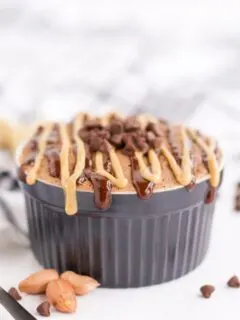 Chocolate peanut butter cake in a mug by chips and peanuts.
