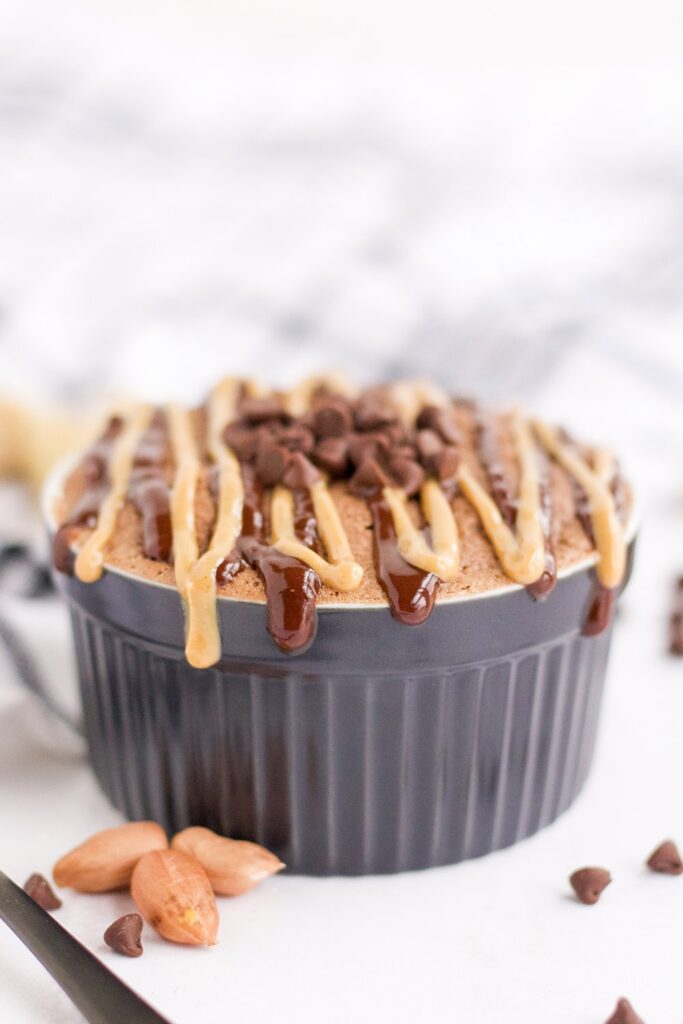 Chocolate peanut butter cake in a mug by chips and peanuts. 