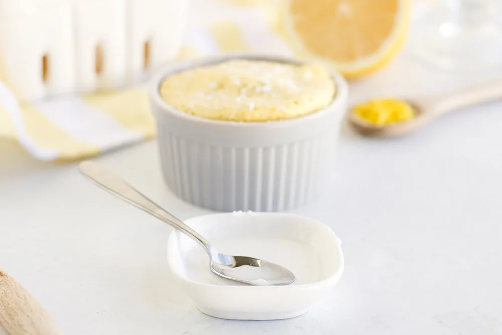 Glaze for lemon mug cake in front of mug cake in a ramekin. 
