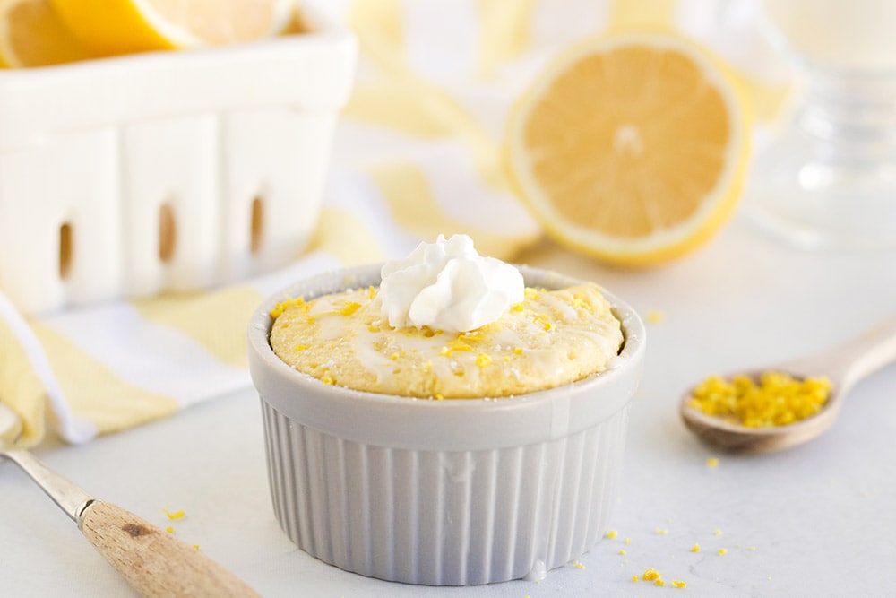 Lemon cake in a ramekin topped with whipped cream. 