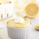 Low-carb lemon mug cake with whipped cream on a table with lemons.