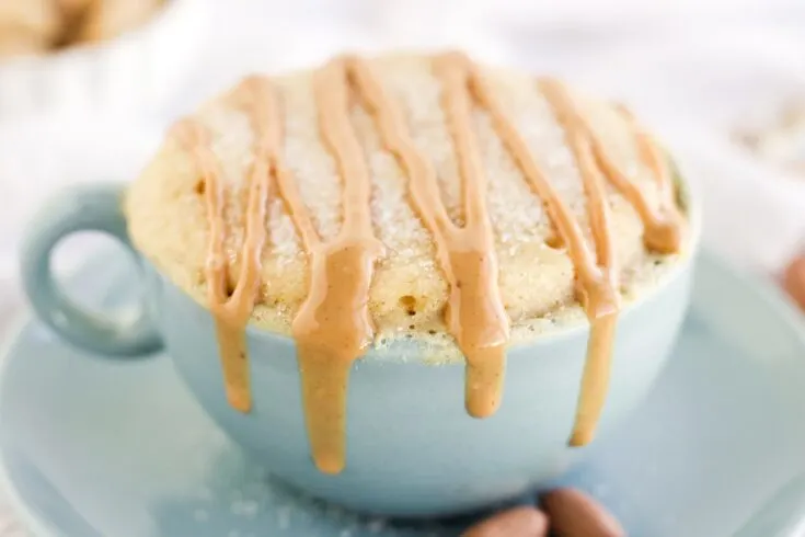 Peanut butter cake with drizzle in a blue mug.
