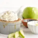 Gray dish with cake in it with green apple and slices on the table.