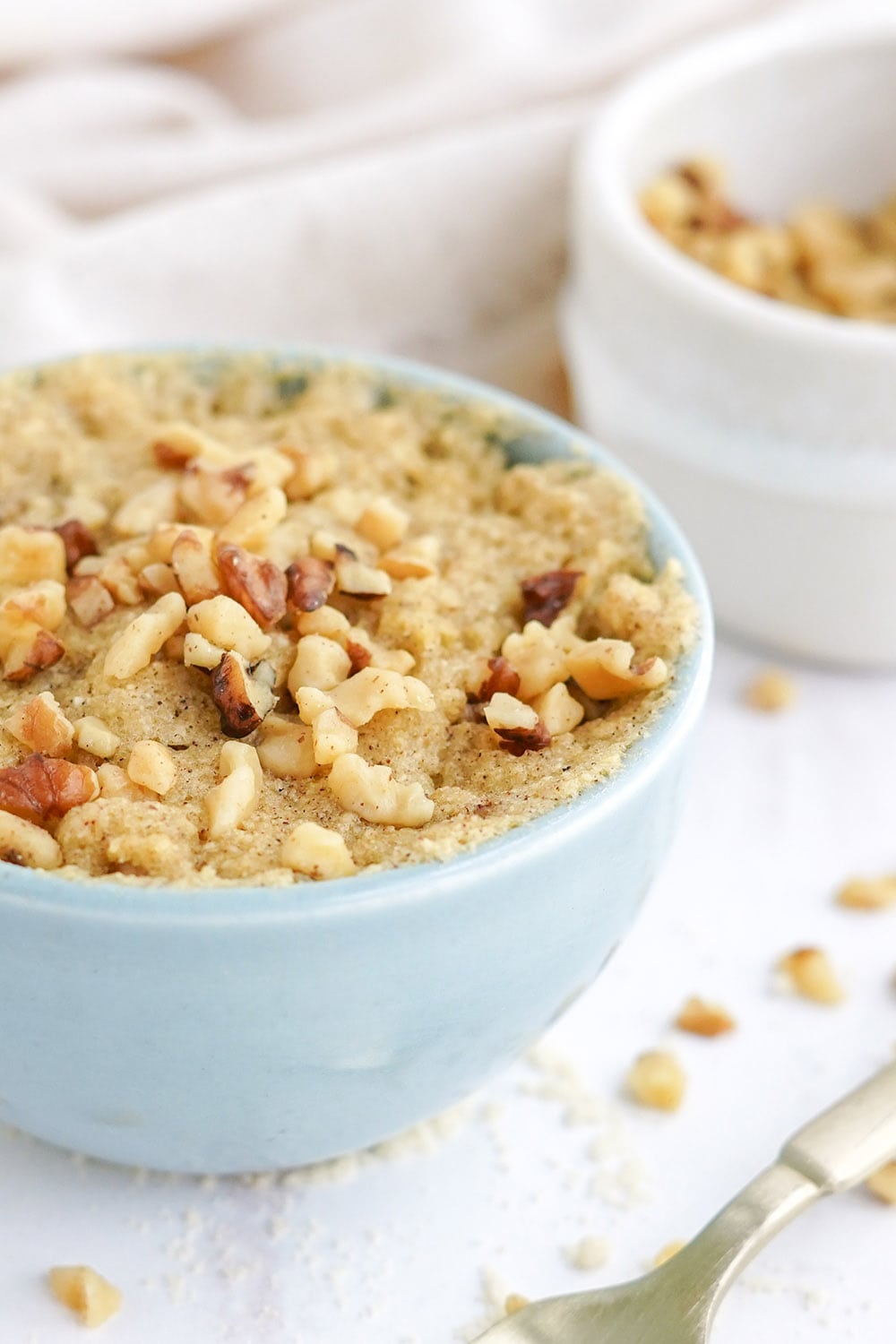 Closeup of a banana mug cake topped with walnuts.