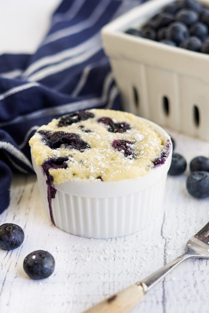 A white ramekin filled with blueberry cake.