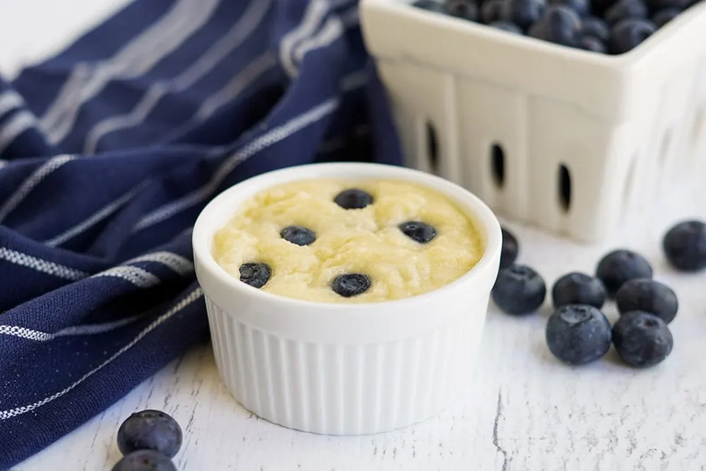 Blueberries in cake batter in a small white dish.