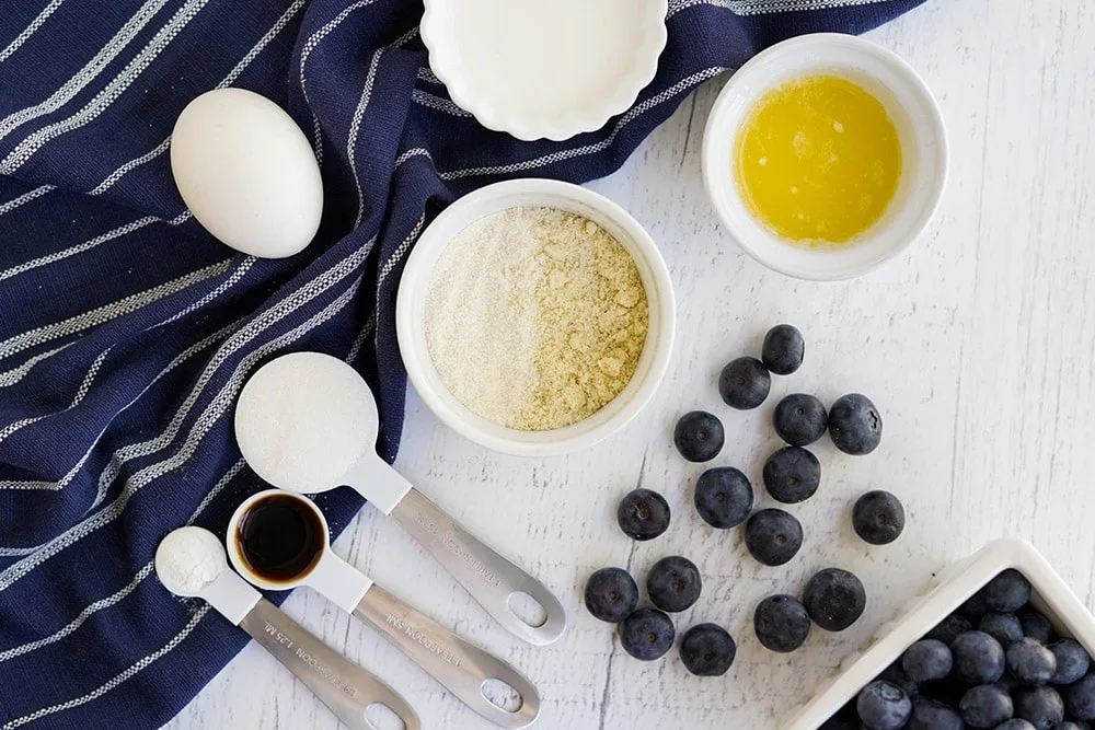 Flat lay of ingredients to make blueberry cake on a table with a blue napkin.