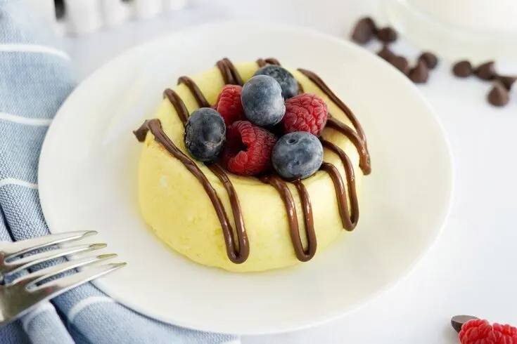 Cheesecake topped with berries and chocolate on a plate.
