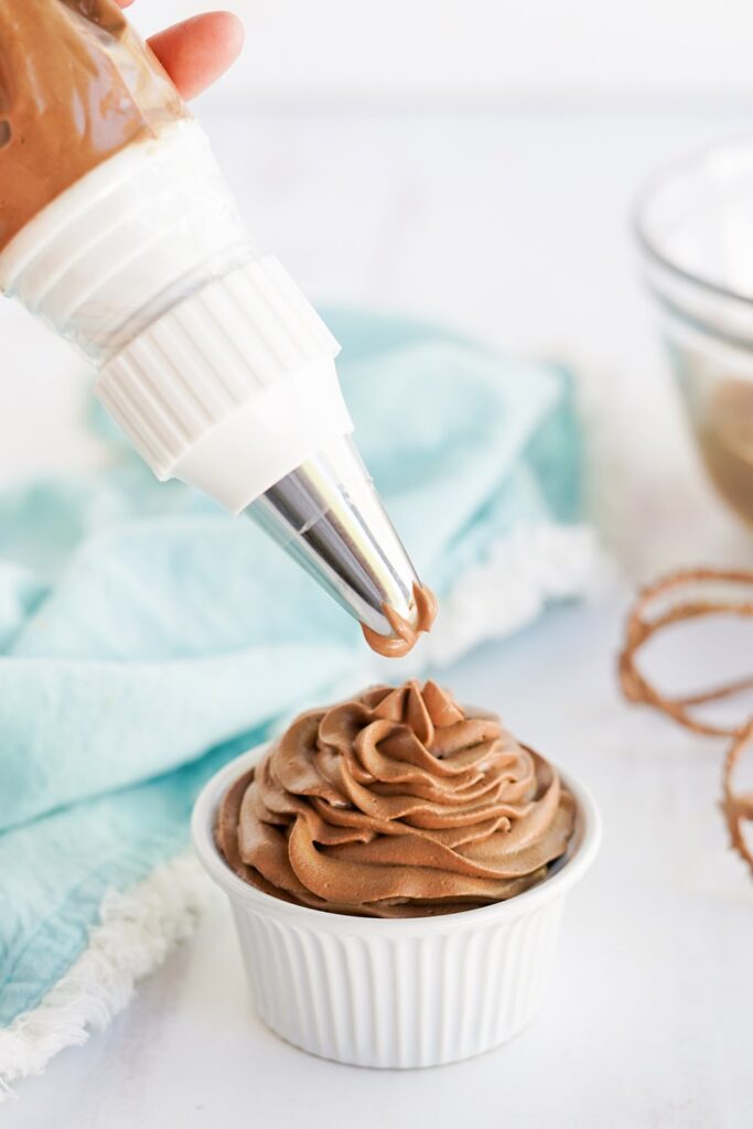 Piping chocolate whipped topping into a small white dish.
