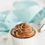 Dish of cocoa whipped topping on a table with a blue napkin.