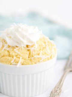 Coconut mug cake in a white dish with a blue napkin.