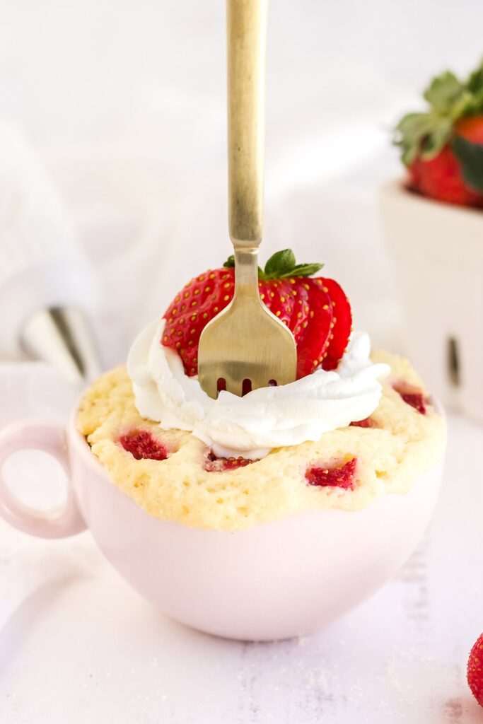 Fork in a mug cake with strawberries.
